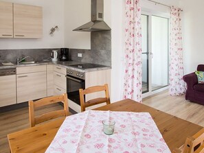 Una cocina con armarios de madera, una estufa y una mesa de comedor con mantel estampado.