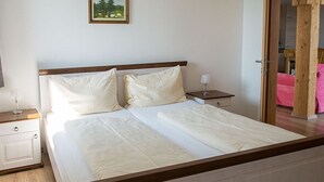Un dormitorio con cama, mesitas de noche y una puerta que da a otra habitación.