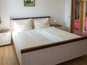 Un dormitorio con cama, mesitas de noche y una puerta que da a otra habitación.