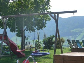 Un parque infantil con tobogán, columpios y un conjunto de columpios.