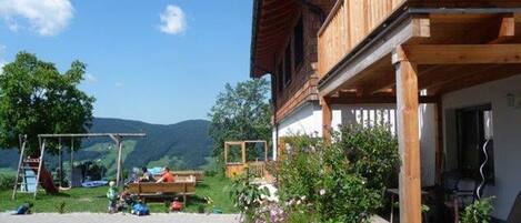 Un bâtiment en bois doté d’un balcon, d’une zone pavée et d’un jardin fleuri.