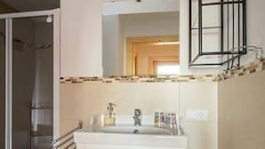 Un baño con un lavamanos blanco, un espejo y una ducha.