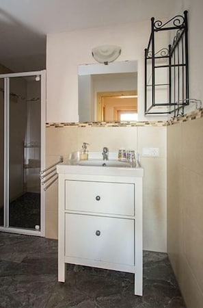 Un baño con un lavamanos blanco, un espejo y una ducha.