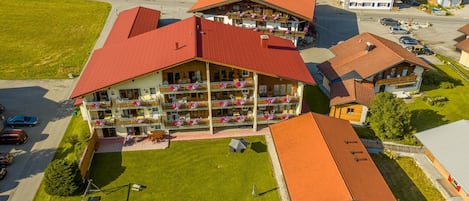 Un hotel de varios pisos con balcones, un estacionamiento y un césped verde.