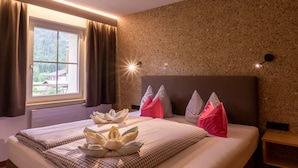 A hotel room with a bed, a window with curtains, a headboard, and a wall with a textured pattern. - No. 8 Bergaster - HAUS fern (Grän)