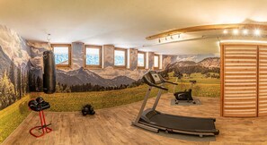 Uma academia em casa com esteira, bicicleta ergométrica, saco de pancadas e equipamentos de ginástica.