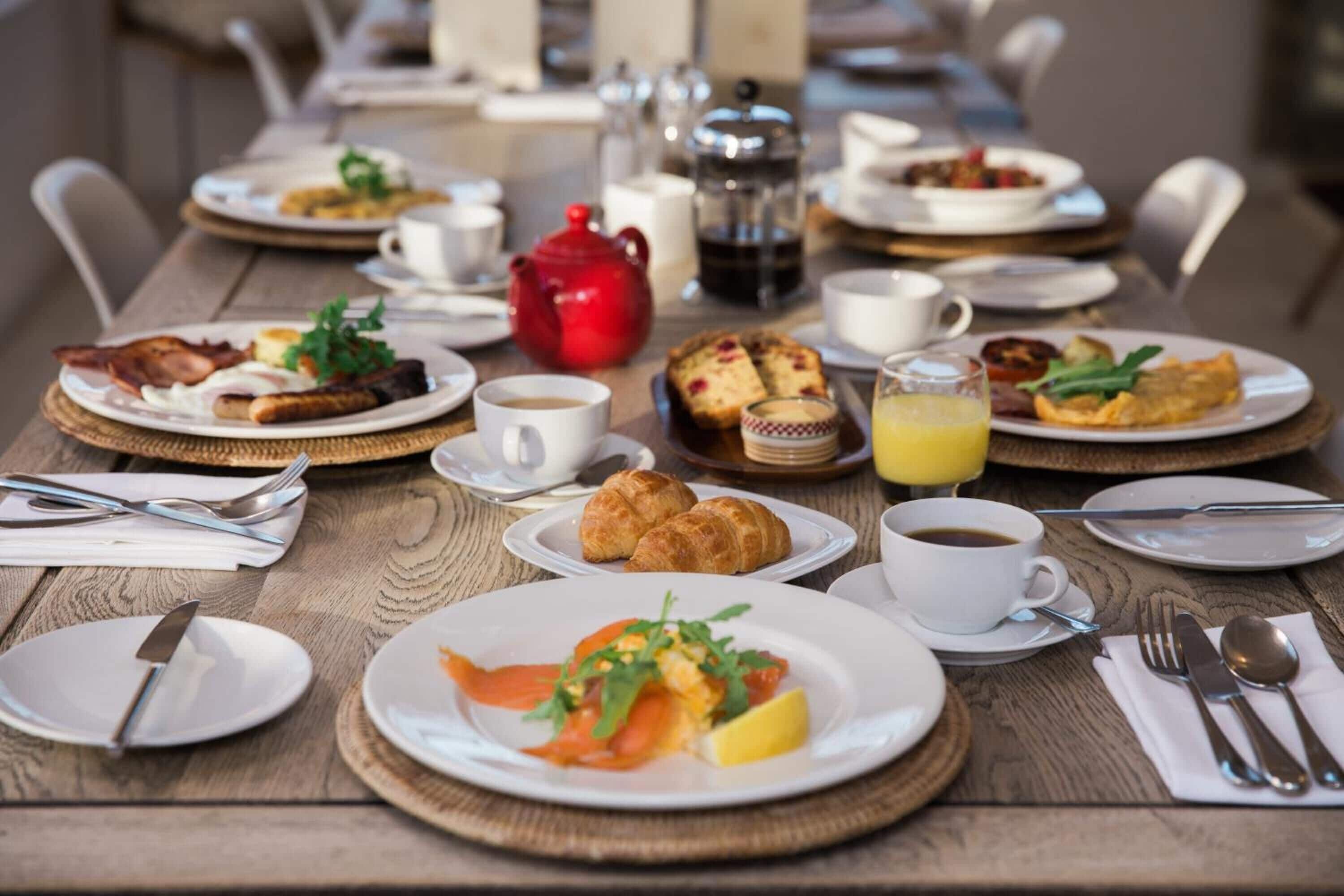 A breakfast buffet with various dishes, coffee, and tea.