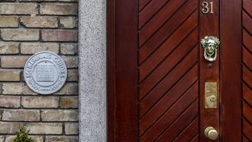 A wooden door with the number 31, a metal plaque on the wall, and a metal door knocker.