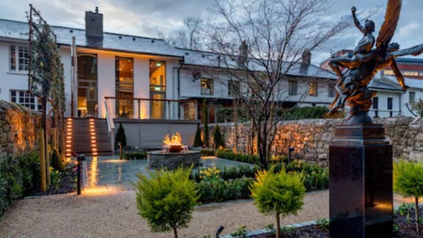 A modern house with a stone wall, a statue, and a fire pit in the garden. - Number 31 (Dublin)