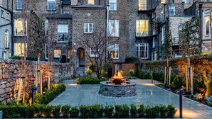 A courtyard with a central fire feature surrounded by stone walls and greenery. - Number 31 (Dublin)