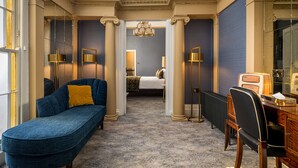 A hotel room with a blue sofa, a desk with a vintage radio, and a bed with a patterned throw. - Number 31 (Dublin)