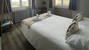 A hotel room with a large bed, two windows, a TV, a desk, and a chair. - Hôtel du Phare (Ouistreham)