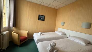 A hotel room with two beds, a chair, a radiator, and a picture on the wall.
