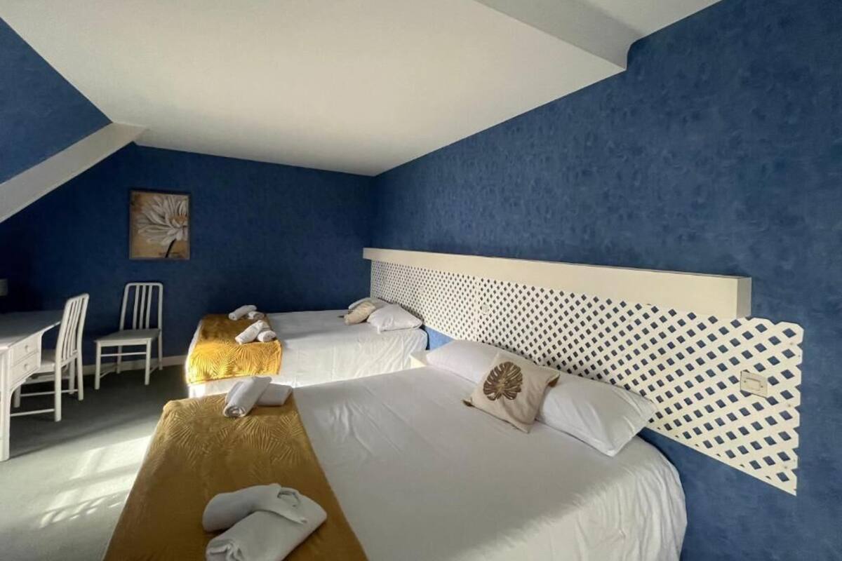Habitación de hotel con dos camas, un escritorio y una silla.