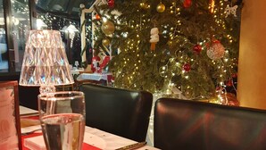 A dining table with a Christmas tree in the background, a lamp, and a menu. - Hôtel du Phare (Ouistreham)