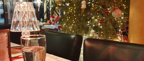 Una mesa de comedor con un árbol de Navidad al fondo, una lámpara y un menú.