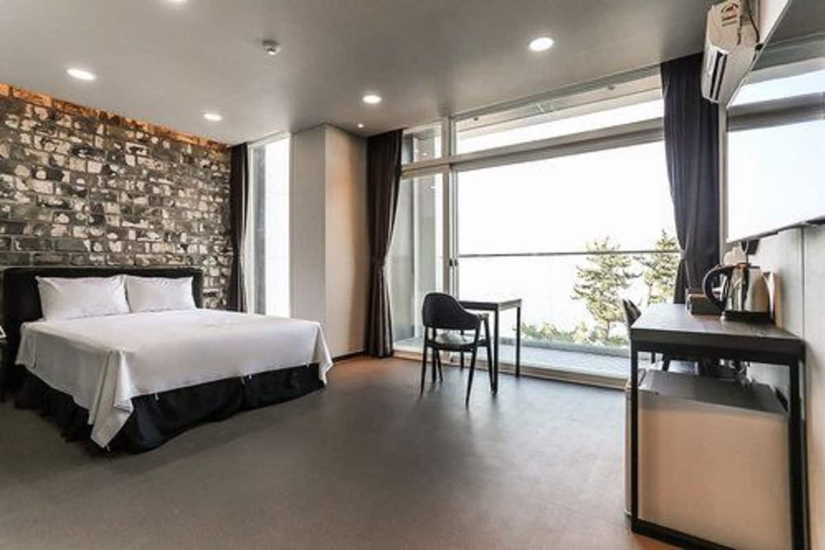 Et moderne hotelværelse med seng, skrivebord og et stort vindue med udsigt.