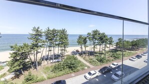 A parking area with cars, a beach, and trees in the background.