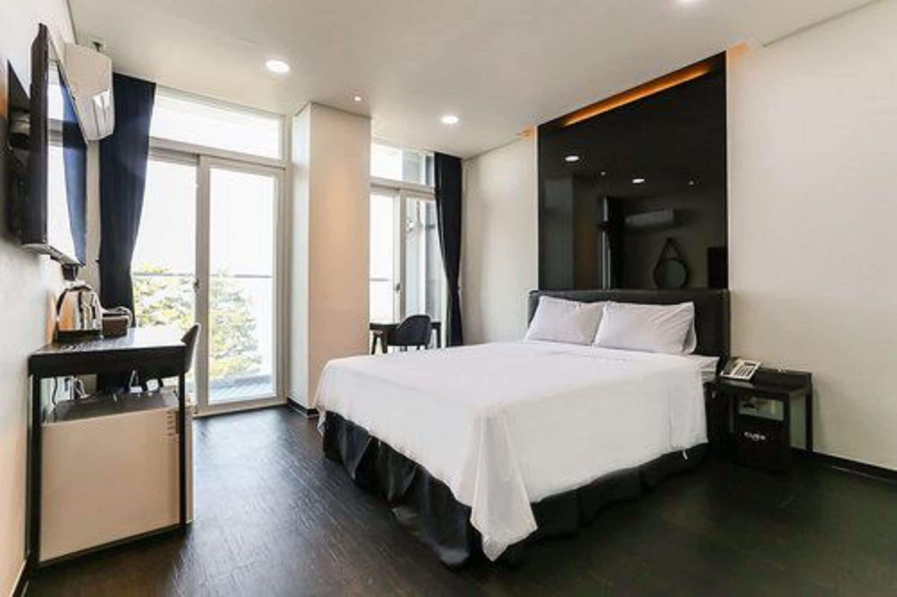 Ein modernes Hotelzimmer mit einem großen Bett, einem Schreibtisch und einem Fernseher.