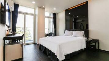 Ein modernes Hotelzimmer mit einem großen Bett, einem Schreibtisch und einem Fernseher.