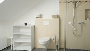 A bathroom with a shower, toilet, and a white shelf unit. - Large apartment with lake view - family holiday Stabauer (4 flowers) (Lindau)
