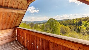 Un balcon en bois offrant une vue sur un paysage boisé.