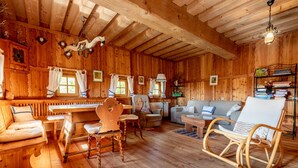 L’intérieur d’un chalet en bois comprend un piano, un coin salon et un fauteuil de lecture.