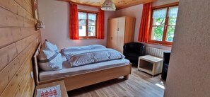 Une pièce en bois avec un lit, une armoire, une chaise et une petite table.