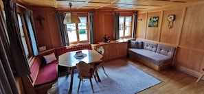 A cozy room with a wooden interior, a dining table with chairs, a bench, and a small sofa. - Vacation with Moses - Holiday apartment (Schoppernau)