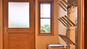 Ein Zimmer mit Holztür, einem Fenster, einem Wandregal und einem kleinen Tisch.