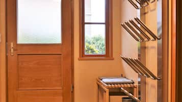 A room with a wooden door, a window, a wall-mounted rack, and a small table.
