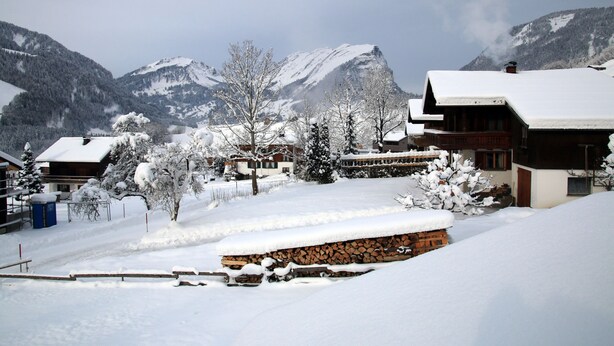 A snow-covered village with wooden buildings, a clear sky, and mountains in the background. - Hochalpe APP#3 - Ritter Anni - Haus Ritter (Schoppernau)