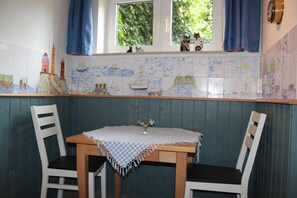A dining area with a table, chairs, and a window with curtains.