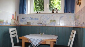 A dining area with a table, chairs, and a window with curtains. - Whg. 4 Swamp swallow basement - Haus Feldmann (Lohme)