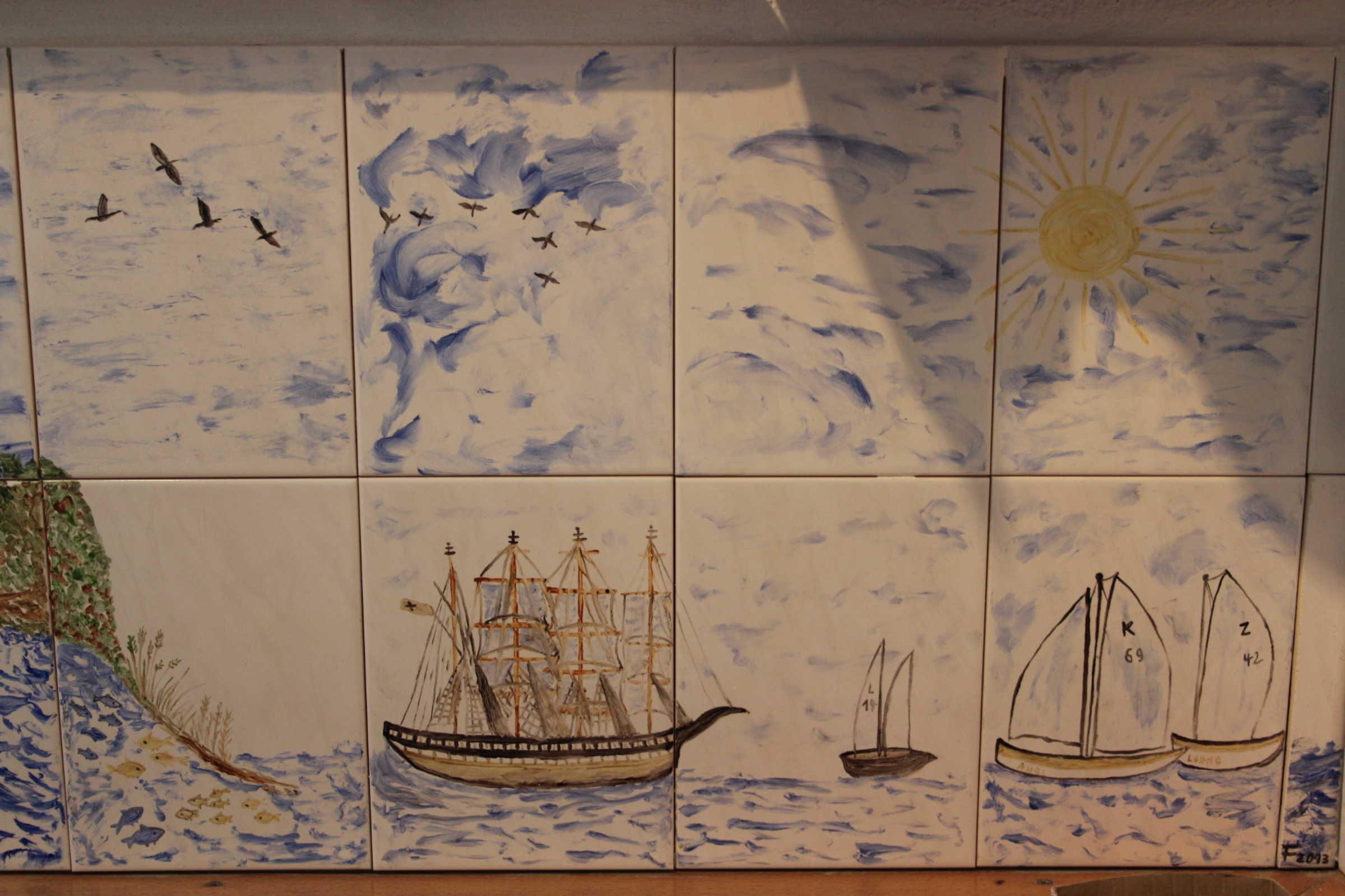 A tiled wall with maritime scenes including ships and birds.