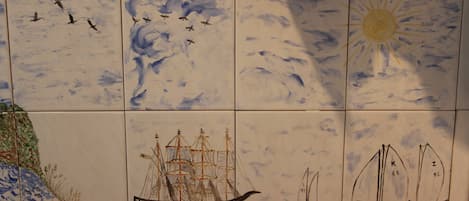 A tiled wall with maritime scenes including ships and birds.