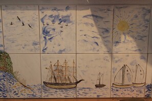 Eine mit Meeresmotiven befliesste Wand, darunter Schiffe und Vögel.