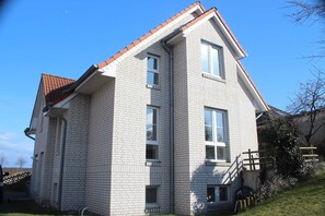 Un bâtiment à deux étages, doté d’un toit recouvert de tuiles rouges, de nombreuses fenêtres et d’un petit escalier menant à l’entrée.