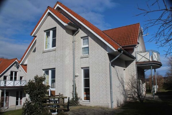 A two-story house with a red-tiled roof, a small balcony, and a garage.