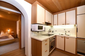 A compact kitchen with wooden cabinets, a microwave, a stove, and a sink.