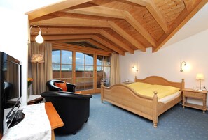 Une chambre avec un lit, une télévision, une chaise, un bureau et une fenêtre donnant sur un beau paysage.