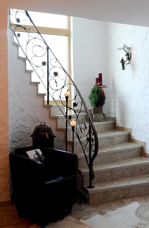 Eine Treppe mit aufwendiger Metallreling, einem kleinen Topfpflanzen und einer Wandleuchte.