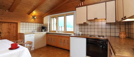 Una cocina con armarios de madera, estufa, fregadero y ventana.