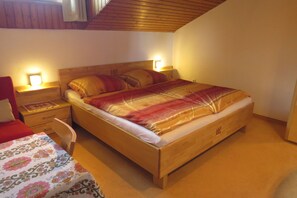 Un dormitorio con una cama de madera, dos mesitas de noche con lámparas, una silla y una colcha de estampado floral.