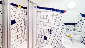 Een badkamer met een betegelde muur, een glazen douchecabine, een wastafel en een spiegel.