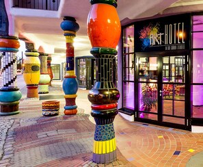Een hotelentree met kleurrijke, uniek ontworpen pilaren en een bord waarop 'ART HOTEL' staat.