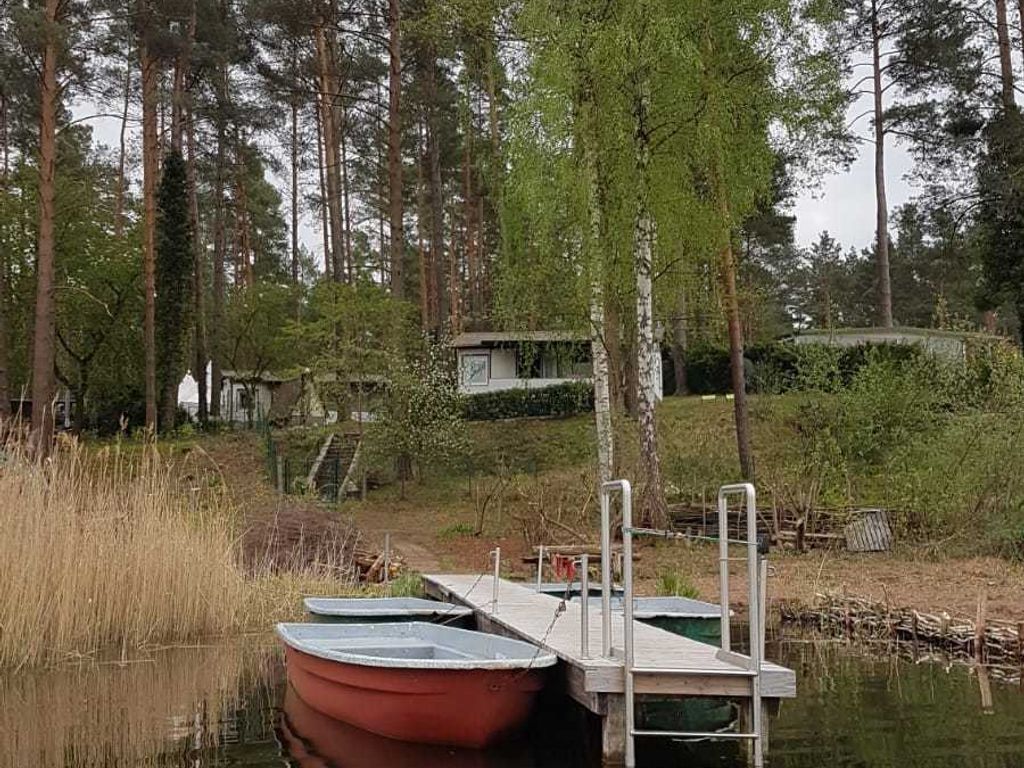 Ein Steg mit Booten, umgeben von Bäumen und einem kleinen Gebäude im Hintergrund.