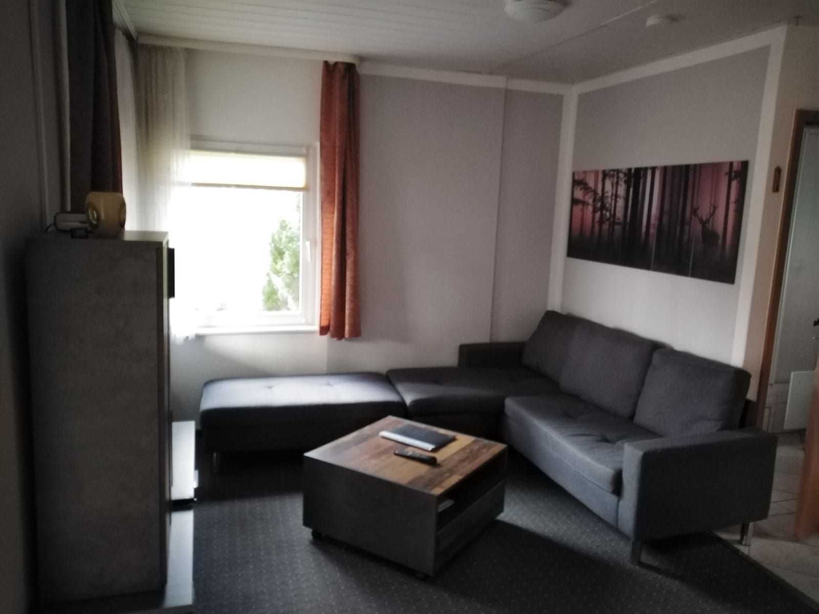 A modern living room with a sectional sofa, a coffee table, and a flat-screen TV.