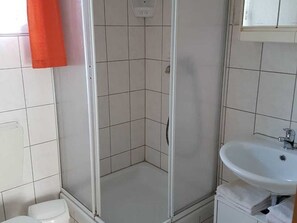 A bathroom with a shower, toilet, and sink.