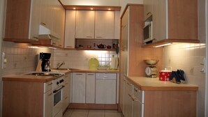 Una cocina compacta con armarios de madera, estufa, lavavajillas y microondas.